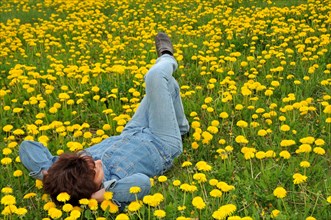 Woman lying on a dandelion meadow