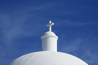 Cross on the dome of a white chapel