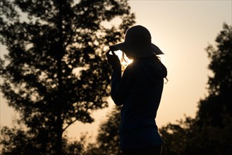 Young woman with hat relaxing in summer sunset sky outdoor