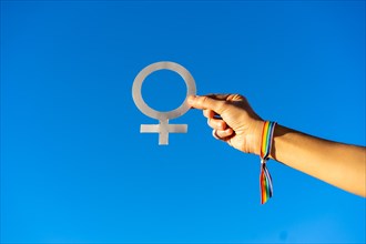 Blue sky background with a hand of a woman with female symbol in favor of feminism