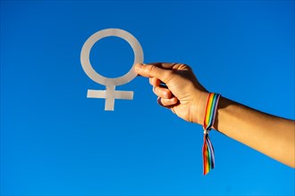 Blue sky background with a hand of a woman with female symbol in favor of feminism