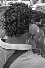 Black-haired New Yorker making a phone call at a telephone pillar
