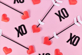 Valentine's day flat lay with cupid's love arrows and text XO on pink background