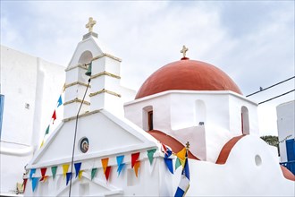 White Cycladic Greek Orthodox Church decorated with flags