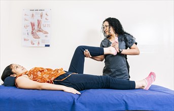 Professional physiotherapist assisting patient in leg rehabilitation