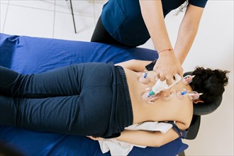 Physiotherapist placing cupping on lying female patient