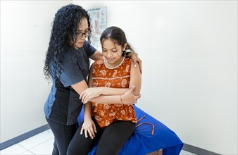 Physiotherapist with female patient assisting and rehabilitating her elbow