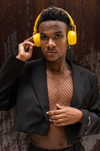 Portrait of a black ethnic man listening to music in wireless yellow headphones