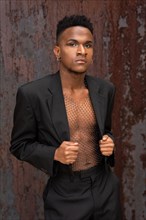 Black ethnic man in a fashion pose on a metallic background with rust