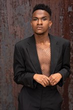 Black ethnic man in a fashion pose on a metallic background with rust