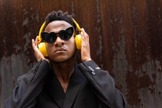 Black ethnic man listening to music wireless yellow headphones