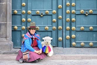 Native woman sitting with a lama in front of the Basilica La Merced Entrance door