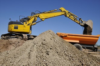 Excavator loading trailers with earth and gravel at a construction site