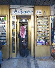 Man with traditional thobe on his head and money in his hand enters a shop
