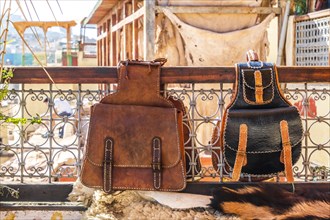 Two leather backpacks exposed for sale on terrace with a tannery view in Fes