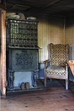 Parlour with tiled stove from 1854 and armchair in a farmhouse