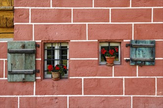 Window with shutters and geraniums on a mill