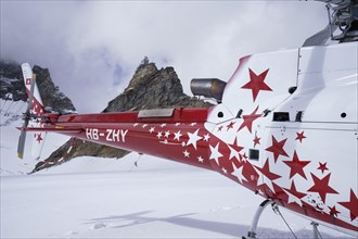 Swiss helicopter tail and engine with red and white stars stand on Aletsch Glacier with a view uphill to the Jungfrau Joch