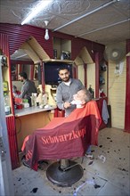 Barber shaves a customer in his shop