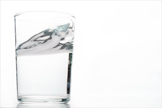 Close-up of a moving glass of crystal clear water isolated on a white background
