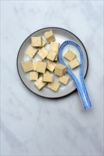 Tofu cubes in bowl with Asian ceramic spoon