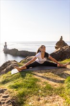 A Latin woman doing yoga exercises in nature by the sea
