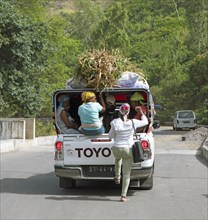 Locals in an aluguer or pickup with roof