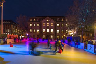 Skaters on a colourfully illuminated artificial ice rink