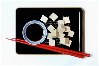Tofu cubes and soy sauce on tray