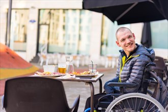 A disabled person in a wheelchair in a restaurant smiling and having fun