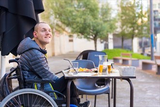 A disabled person eating on the terrace of a restaurant