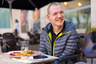 Portrait of a disabled person in a wheelchair in a restaurant smiling