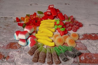 Several types of assorted jelly candies on a brick background