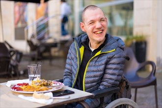 Portrait of a disabled person in a wheelchair in a restaurant smiling and having fun