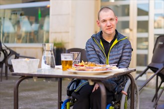 A disabled person in a wheelchair in a restaurant waiting to eat