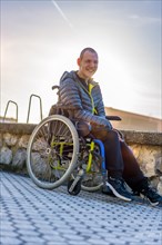 Portrait of a disabled person in a wheelchair having fun in a park at sunset