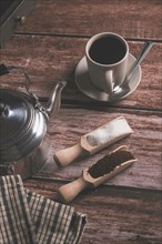 Zenithal view of a coffee cup with milk jug and wooden spoons on a wooden table with text space