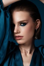 Beautiful woman with blue fabric and classic arrows art make-up