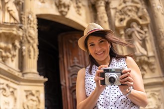 Woman tourist with hat visiting a church and taking photos with a camera