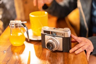 A hand of a tourist with a photo camera having a tea in a cafeteria