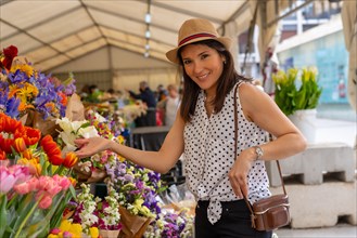 A pretty tourist with a photo camera visiting a flower market