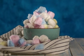 Colored cotton balls in various containers on a blue background
