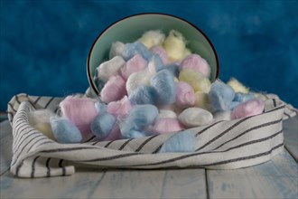 Colored cotton balls in various containers on a blue background