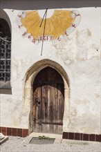 Sundial and wooden door at the church of St Laurentius