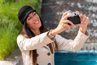 A tourist woman taking a selfie with the photo camera on her summer vacation in the city