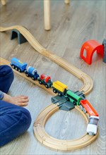Unrecognizable child playing with a wooden train on the floor in his bedroom