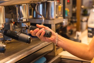 Hands of female coffee shop owner preparing coffee in a coffee machine