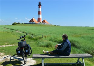 Woman sitting on a bench at the lighthouse Westerheversand