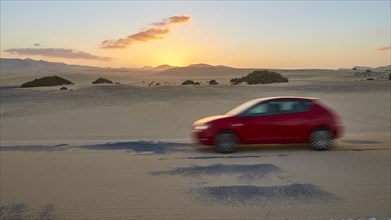Red blurred car on sandy asphalt road