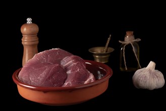 Raw beef tenderloin on a earthenware casserole isolated on black background and copy space